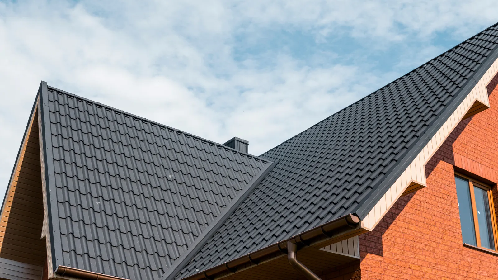 A steep gable peak covered in dark metal tile roofing panels